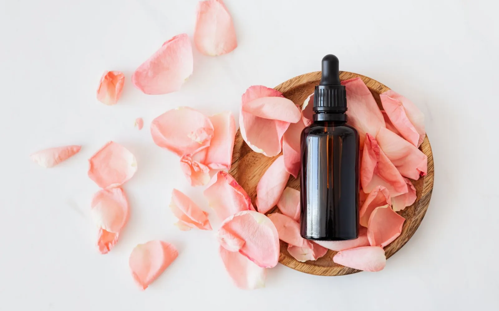 Amber dropper bottle on pale rose petals