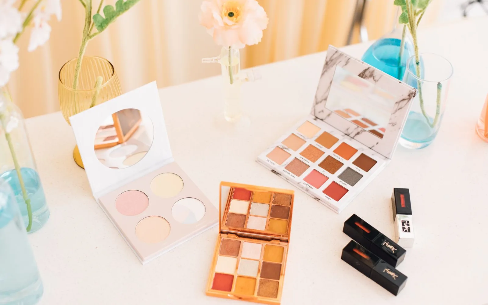 Open makeup palettes on a pale table