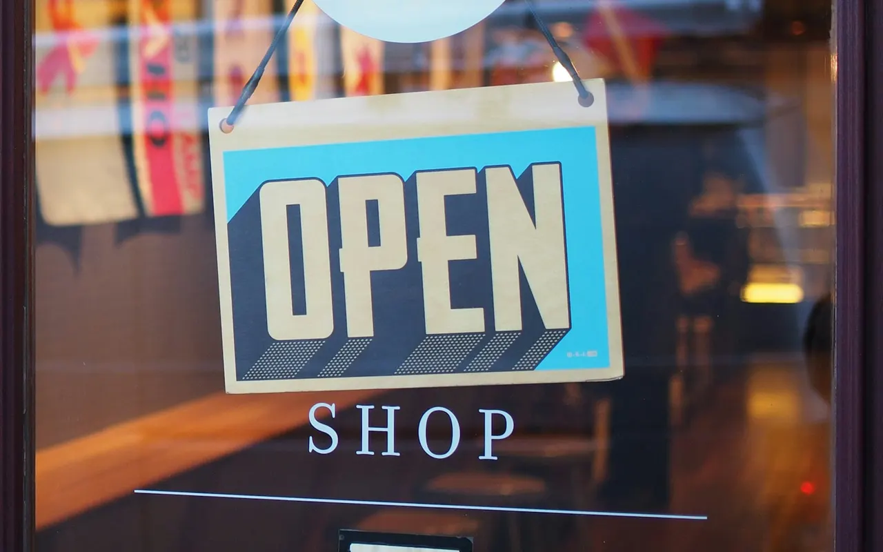 Open shop sign hanging in a storefront window