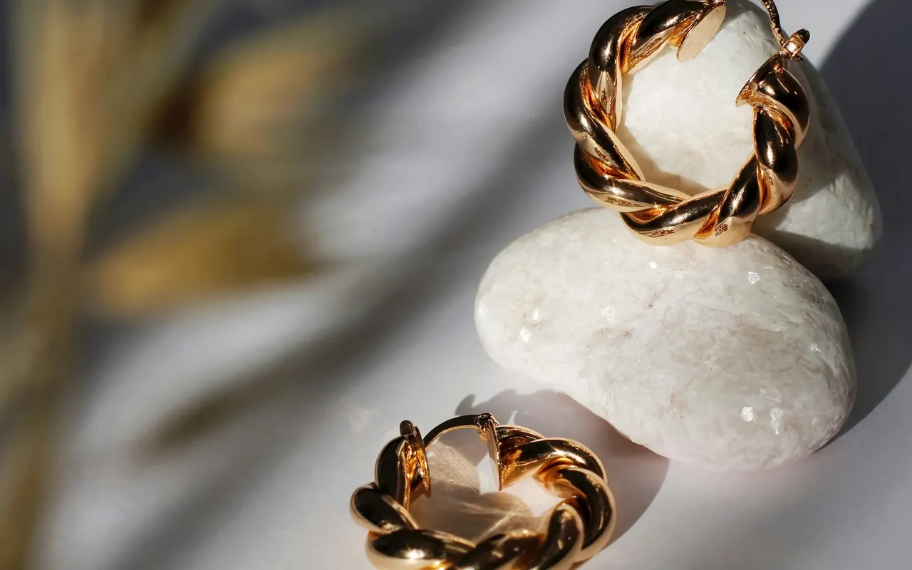 Gold twisted hoop earrings on white stones