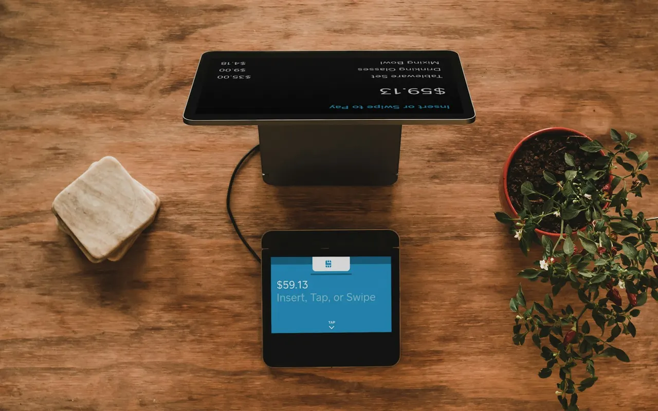 Checkout terminal on a wooden counter next to a plant
