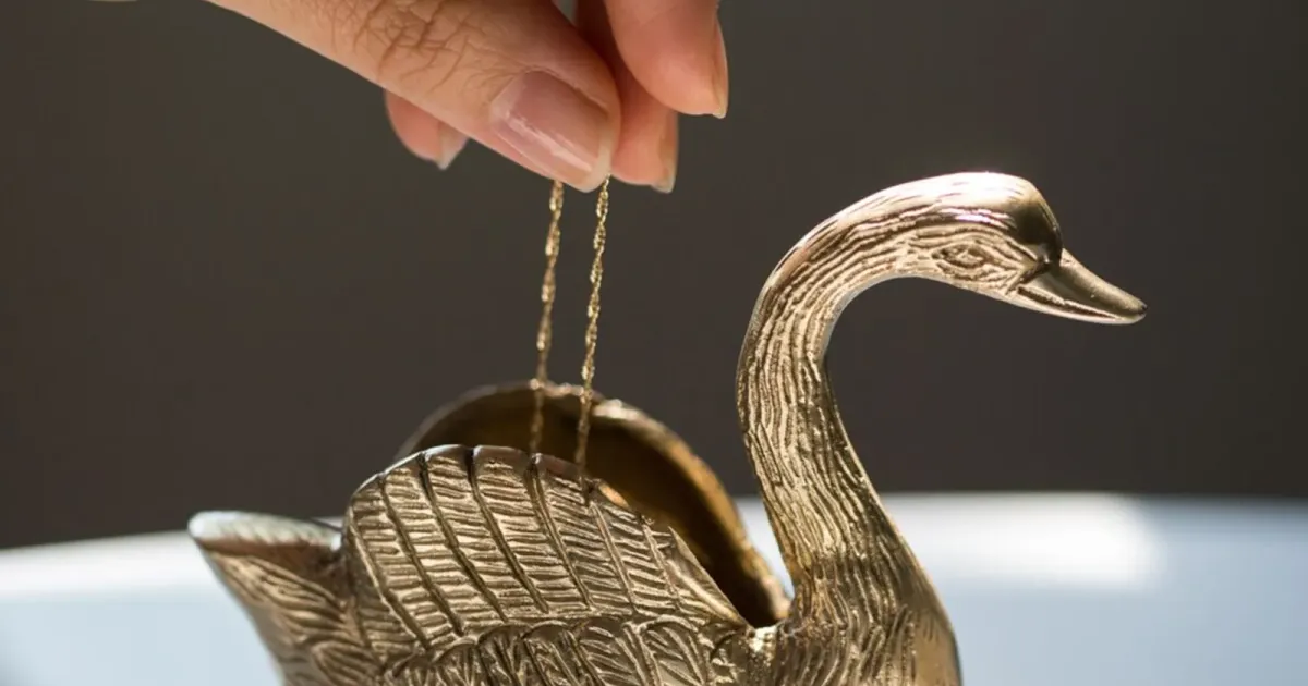Gold chain over a brass swan dish — official jewelry still